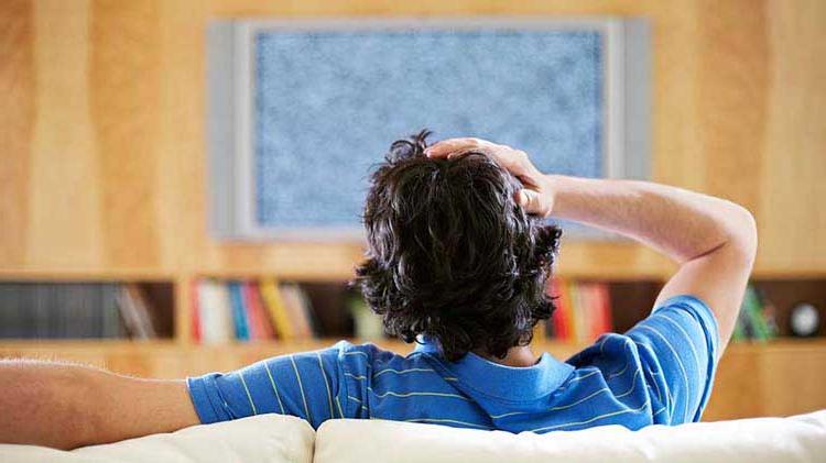 Man looking at static on a TV screen.