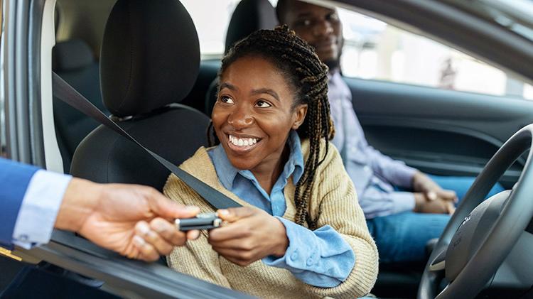 Young woman receiving keys to a new car.