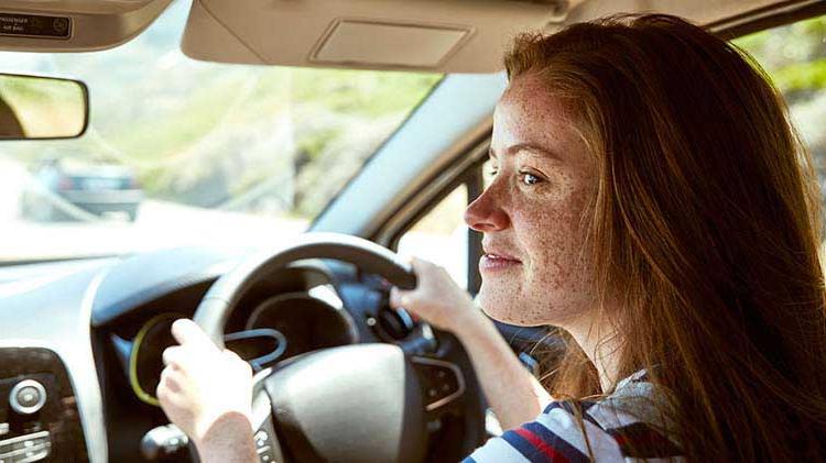 Teenage girl driving with both hands on the wheel.